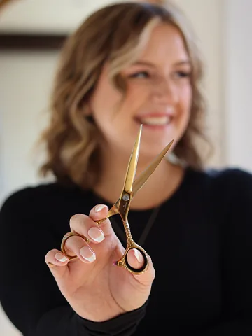 Gold hair-cutting scissors held by a stylist