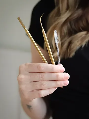 Lash and brow tools held by a beauty professional